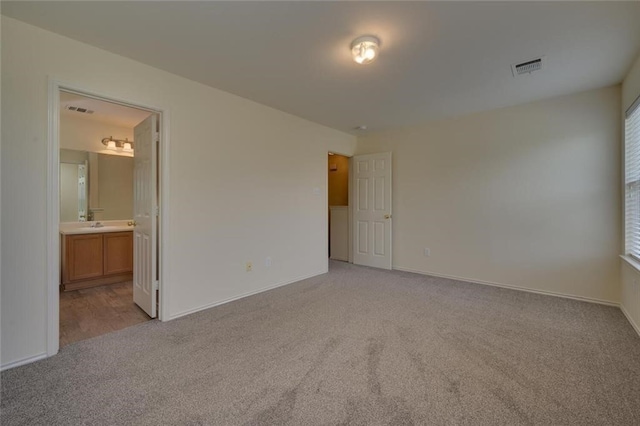 unfurnished bedroom with connected bathroom and light colored carpet