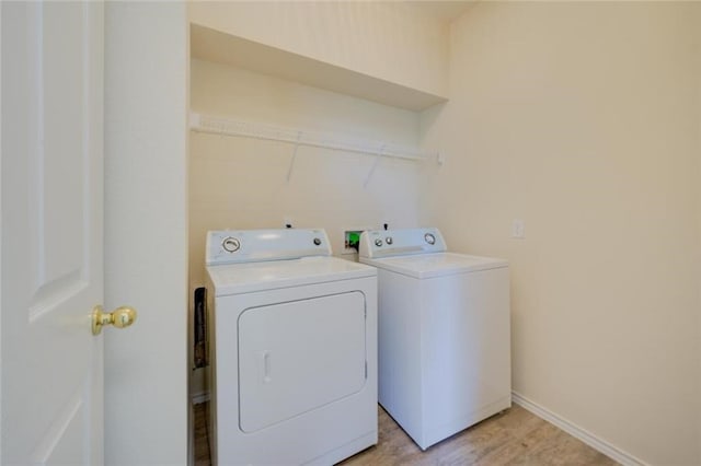 washroom with washing machine and clothes dryer and light hardwood / wood-style floors