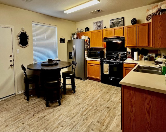 kitchen featuring sink, black range, stainless steel fridge with ice dispenser, and light wood-type flooring