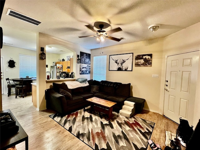 living room featuring a healthy amount of sunlight, a textured ceiling, light hardwood / wood-style floors, and ceiling fan