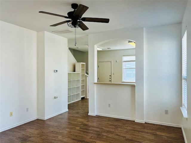 spare room featuring a ceiling fan, visible vents, wood finished floors, baseboards, and arched walkways