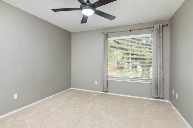 carpeted spare room with ceiling fan and baseboards