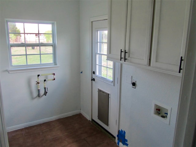 clothes washing area with dark tile patterned flooring, electric dryer hookup, washer hookup, and cabinets