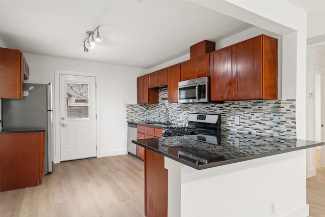 kitchen with kitchen peninsula, stainless steel appliances, sink, light hardwood / wood-style floors, and tasteful backsplash