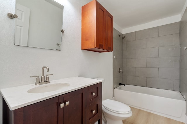 full bathroom with tiled shower / bath, vanity, wood-type flooring, and toilet