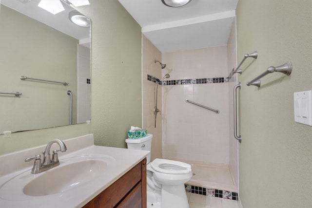 bathroom with tile patterned flooring, vanity, a skylight, toilet, and a tile shower