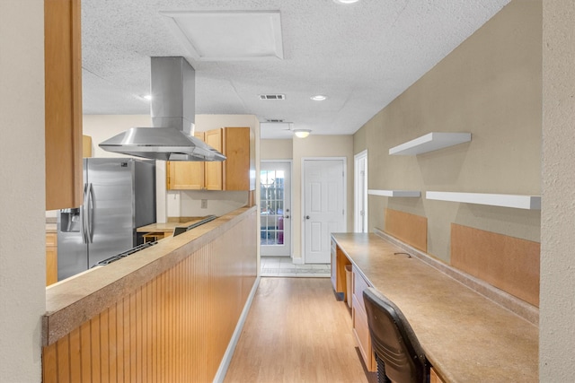 kitchen featuring a textured ceiling, range, stainless steel refrigerator with ice dispenser, island range hood, and light wood-type flooring