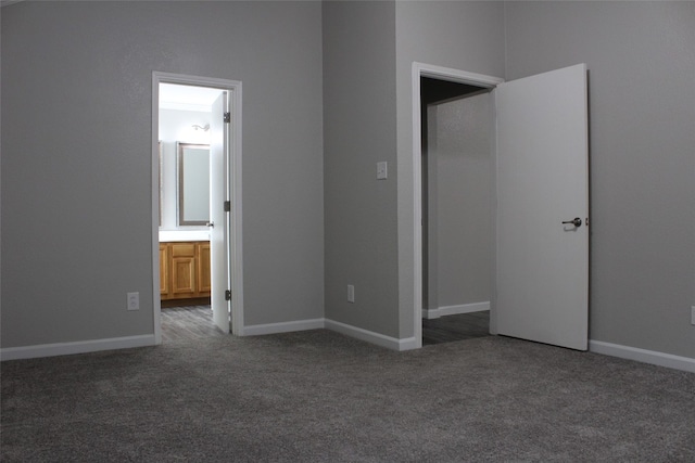 unfurnished bedroom featuring ensuite bath and dark carpet