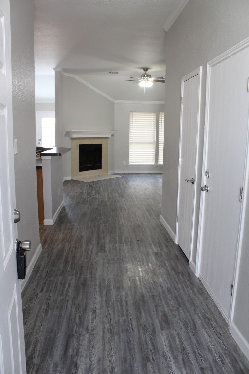 unfurnished living room with crown molding, ceiling fan, and dark hardwood / wood-style flooring