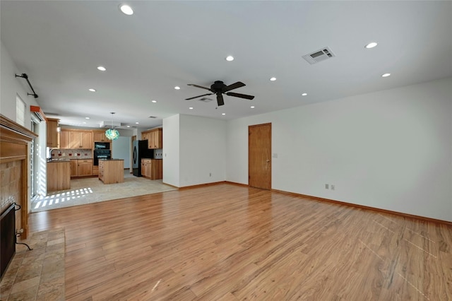 unfurnished living room with light hardwood / wood-style floors, sink, and ceiling fan