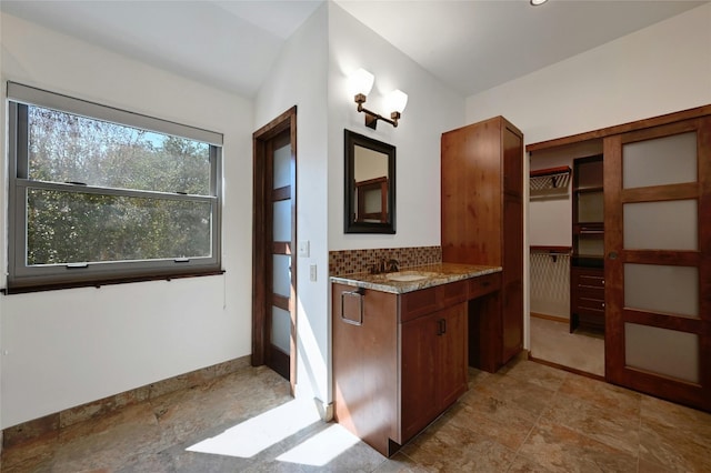 bathroom featuring vanity, backsplash, and lofted ceiling