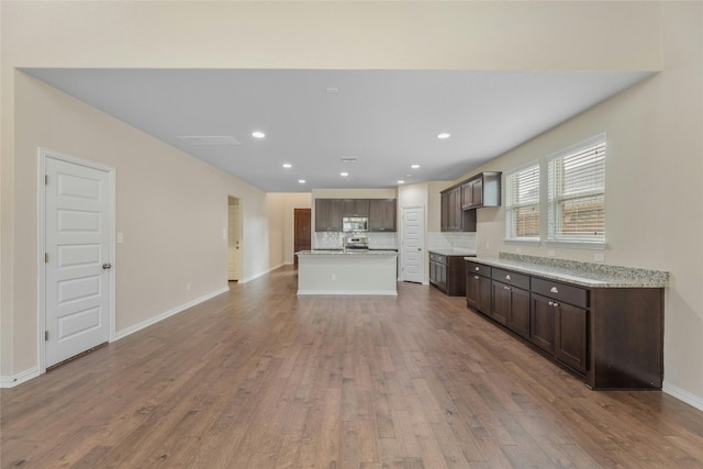 kitchen with decorative backsplash, dark brown cabinetry, hardwood / wood-style flooring, and stainless steel appliances