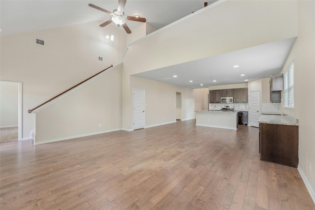 unfurnished living room with hardwood / wood-style flooring, high vaulted ceiling, and ceiling fan