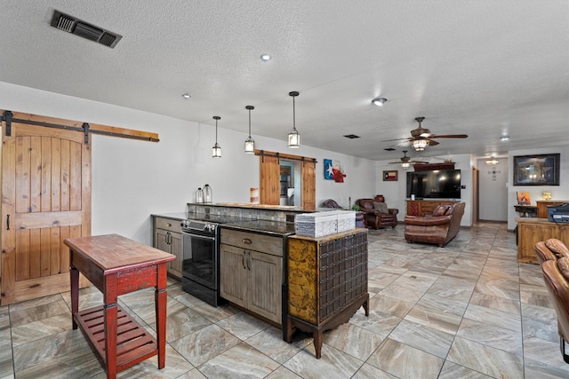 kitchen with a barn door, ceiling fan, hanging light fixtures, and a textured ceiling