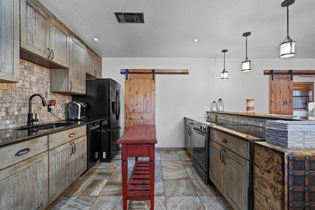 kitchen with decorative backsplash, black appliances, sink, pendant lighting, and a barn door