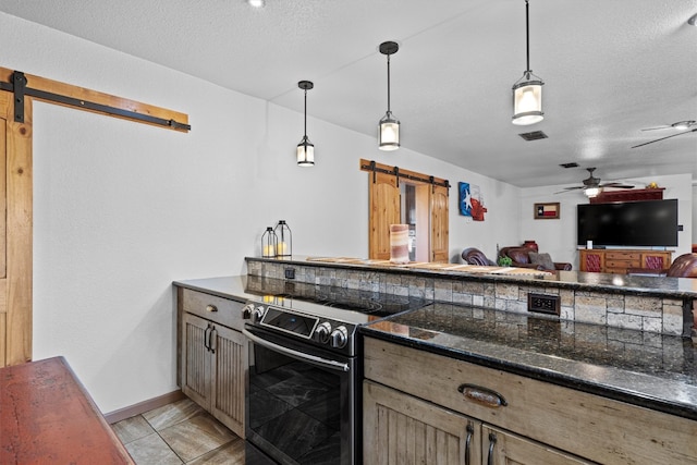 kitchen with pendant lighting, a barn door, dark stone counters, and electric range