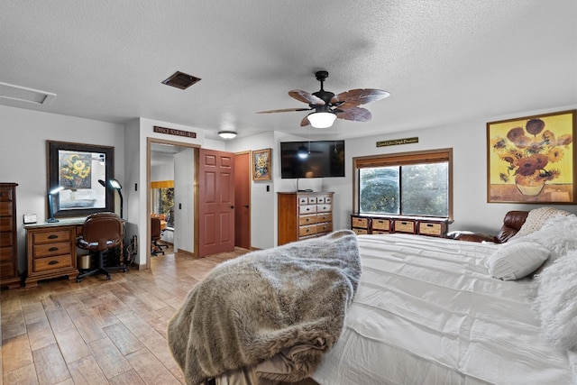 bedroom with ceiling fan, light wood-type flooring, and a textured ceiling