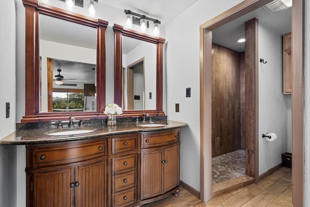 bathroom featuring hardwood / wood-style flooring, ceiling fan, walk in shower, and vanity