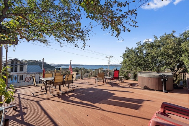 deck with a water view and a hot tub