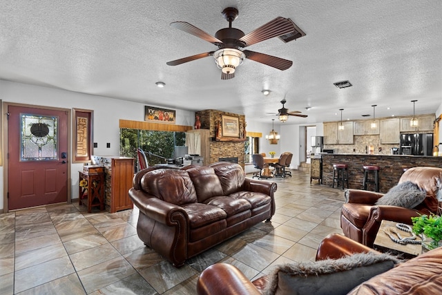 living room with ceiling fan, a fireplace, and a textured ceiling