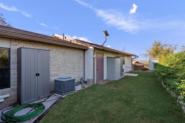 exterior space with central AC unit and a lawn