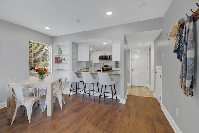 kitchen with dark hardwood / wood-style flooring, sink, a breakfast bar, white cabinets, and kitchen peninsula