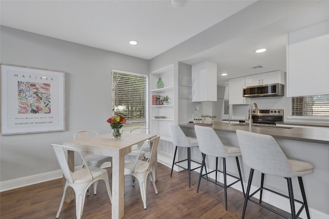 kitchen with stainless steel appliances, a breakfast bar area, white cabinets, and dark hardwood / wood-style flooring