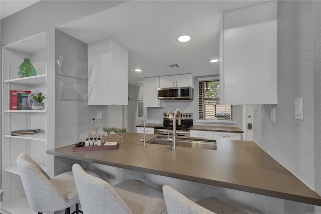 kitchen with white cabinets, sink, kitchen peninsula, and appliances with stainless steel finishes