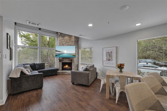 living room with dark hardwood / wood-style floors and a stone fireplace