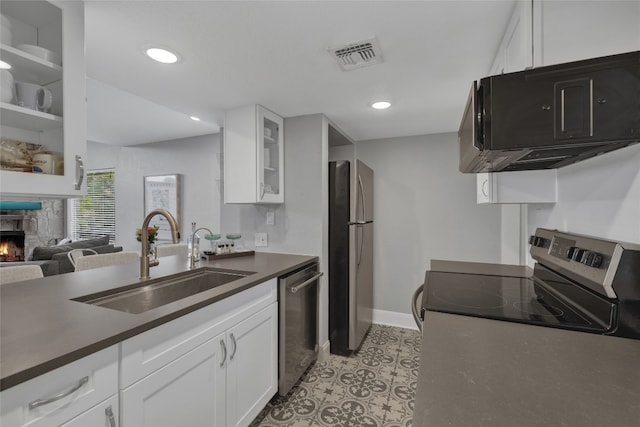 kitchen featuring a fireplace, white cabinetry, sink, and stainless steel appliances