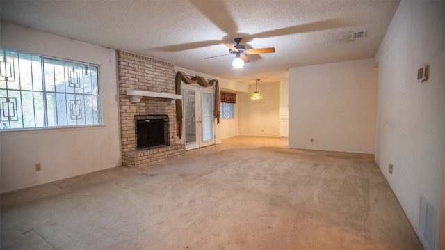 unfurnished living room featuring a textured ceiling, light colored carpet, a fireplace, and ceiling fan