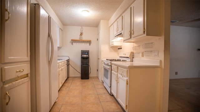 kitchen featuring white appliances, a textured ceiling, light tile patterned floors, and white cabinetry