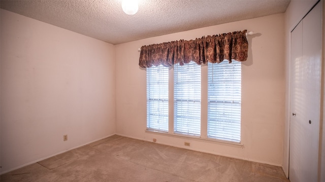 empty room featuring light carpet and a textured ceiling