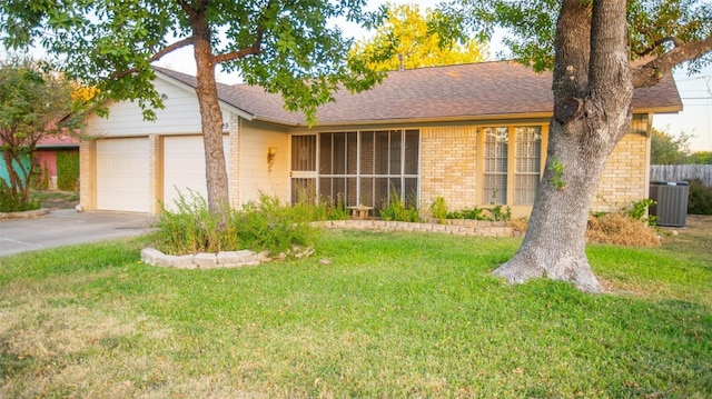 ranch-style house with an attached garage, a front lawn, central AC unit, brick siding, and driveway