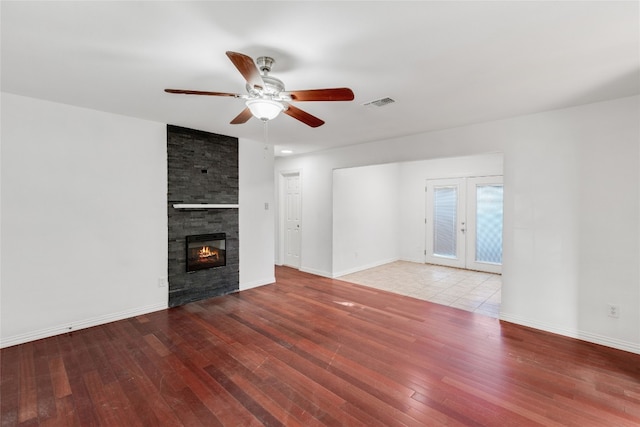 unfurnished living room featuring french doors, hardwood / wood-style flooring, a fireplace, and ceiling fan