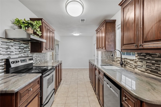 kitchen featuring tasteful backsplash, light stone countertops, sink, stainless steel appliances, and light tile patterned floors