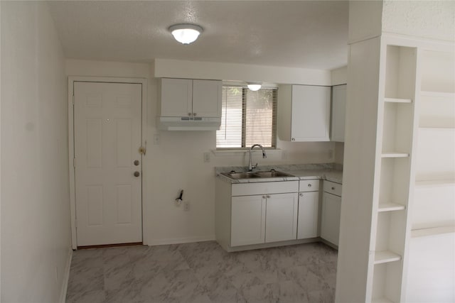 kitchen featuring sink, white cabinetry, and a textured ceiling