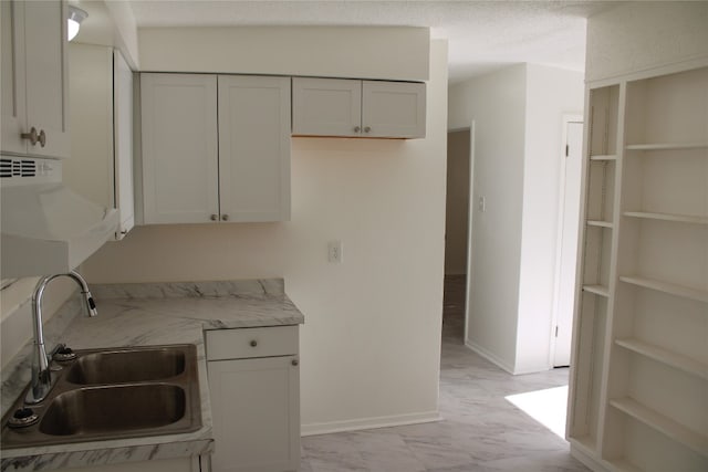 kitchen featuring white cabinetry, sink, and a textured ceiling