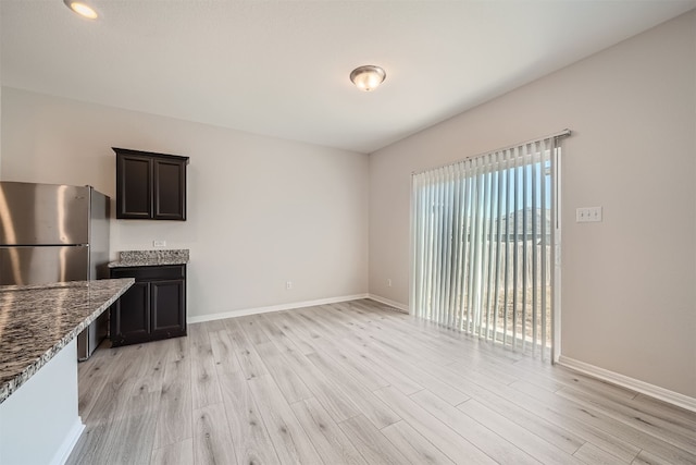 kitchen with stainless steel fridge, light hardwood / wood-style flooring, and stone counters