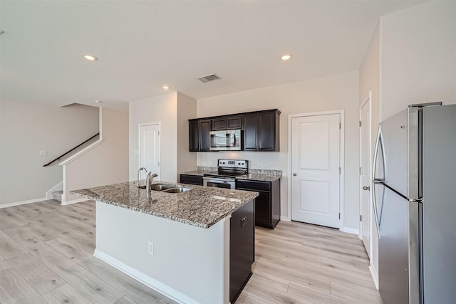 kitchen featuring sink, stone countertops, stainless steel appliances, and a kitchen island with sink