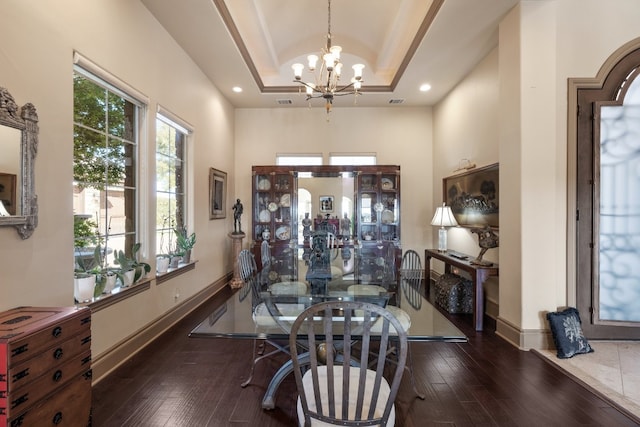 dining room with dark wood-type flooring, a notable chandelier, and a raised ceiling