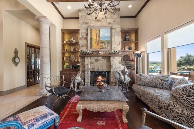 living room with ornamental molding, decorative columns, a stone fireplace, and hardwood / wood-style flooring