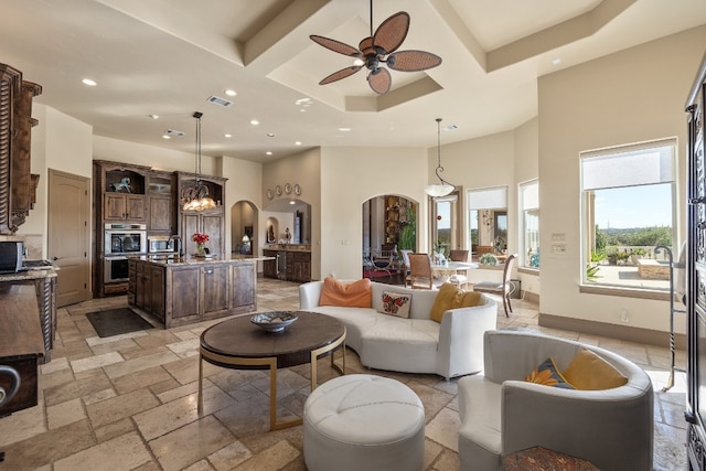 living room featuring coffered ceiling, a high ceiling, and ceiling fan