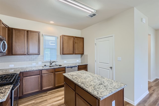 kitchen featuring decorative backsplash, light hardwood / wood-style flooring, stainless steel appliances, sink, and a center island