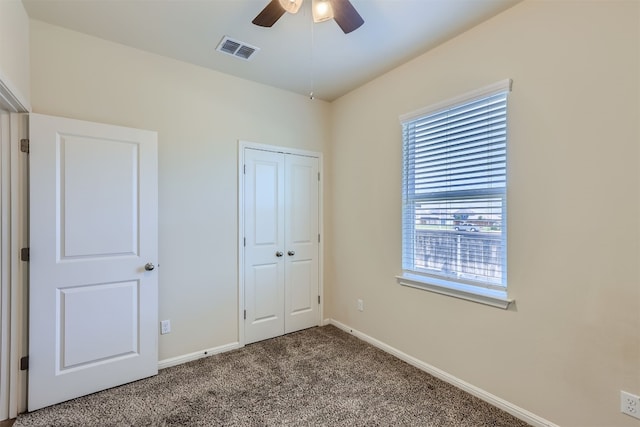 unfurnished bedroom with a closet, carpet, and ceiling fan