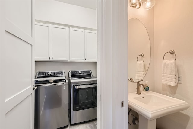 laundry area with sink, washer and dryer, light hardwood / wood-style floors, and cabinets