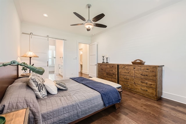 bedroom featuring ensuite bathroom, a barn door, ceiling fan, and dark hardwood / wood-style flooring