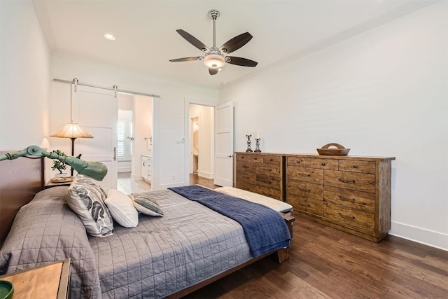 1100 Railroad Ave, Georgetown, TX 78626 - bedroom with connected bathroom, a barn door, recessed lighting, baseboards, and wood finished floors