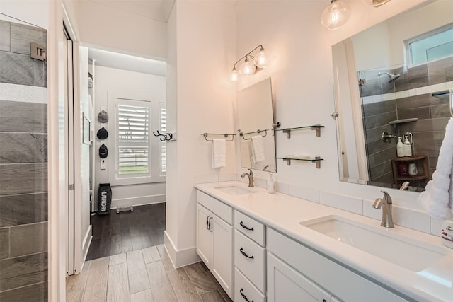 bathroom featuring vanity, a tile shower, a healthy amount of sunlight, and hardwood / wood-style floors