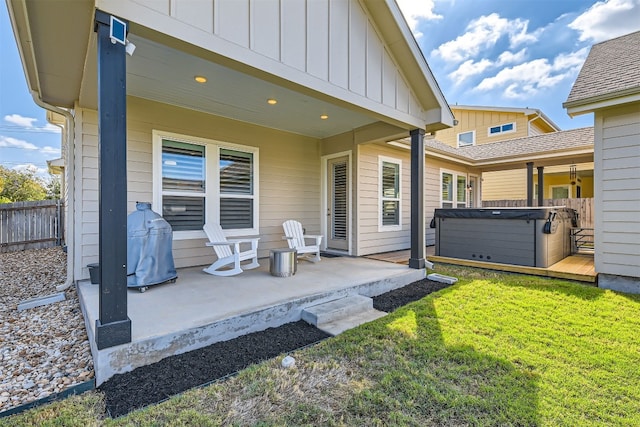 rear view of property featuring a hot tub, a patio, and a lawn